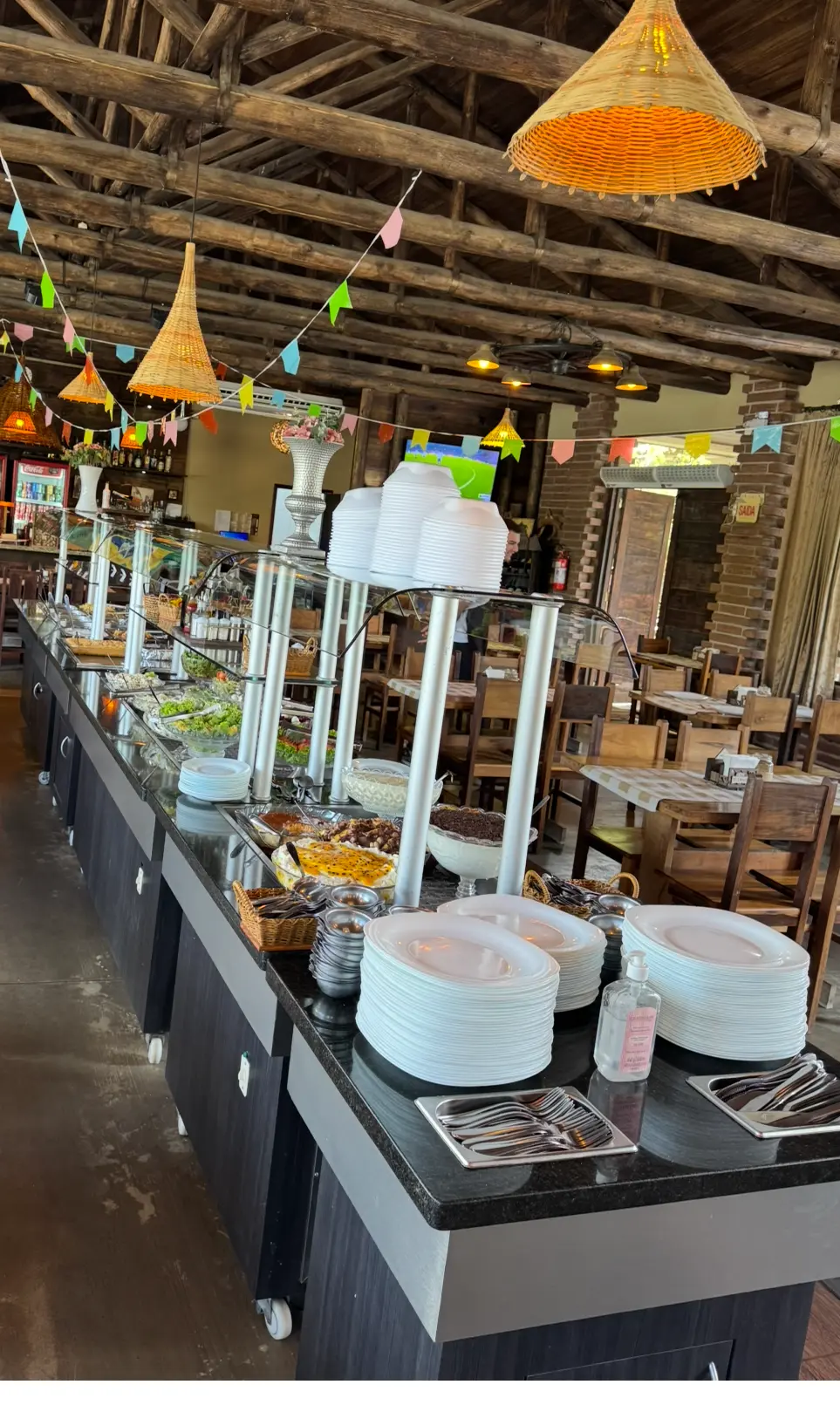 Salão do Villa Maria com buffet servido e mesas de madeira